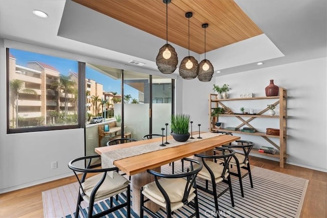 dining space featuring a tray ceiling, wooden ceiling, and light hardwood / wood-style floors