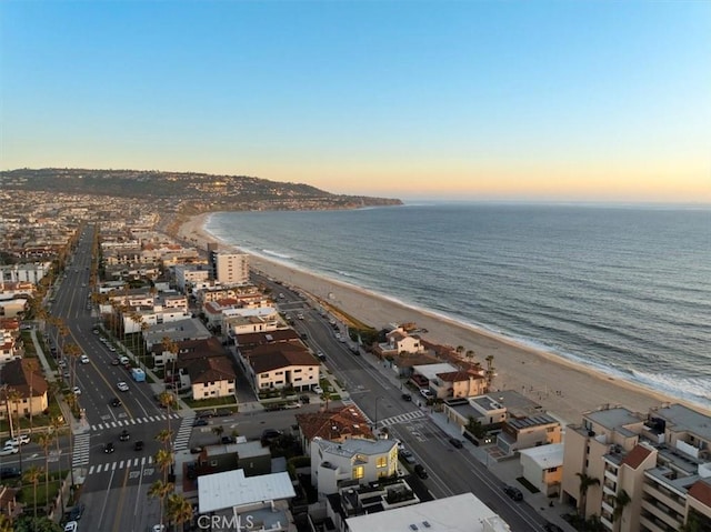 aerial view at dusk featuring a beach view and a water view