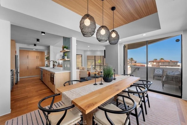 dining room featuring sink, wood ceiling, and light hardwood / wood-style flooring