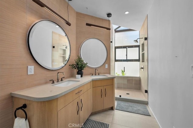 bathroom with vanity, a shower with shower door, tile patterned floors, and tile walls