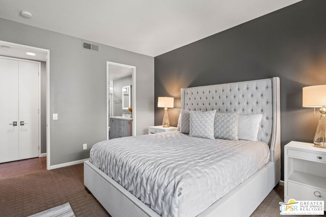 bedroom with dark colored carpet and ensuite bathroom