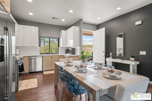 kitchen featuring white cabinets, a healthy amount of sunlight, stainless steel appliances, and dark wood-type flooring