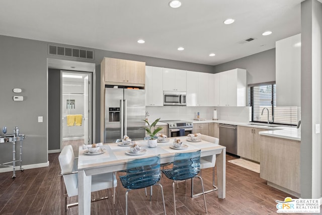 kitchen with a breakfast bar, stainless steel appliances, dark wood-type flooring, and sink