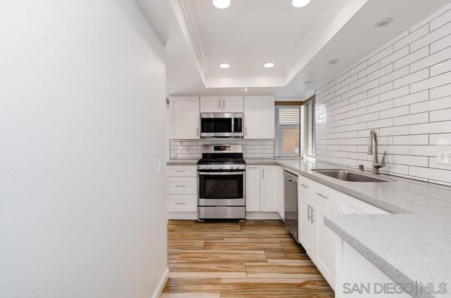 kitchen with sink, stainless steel appliances, tasteful backsplash, light hardwood / wood-style flooring, and white cabinets