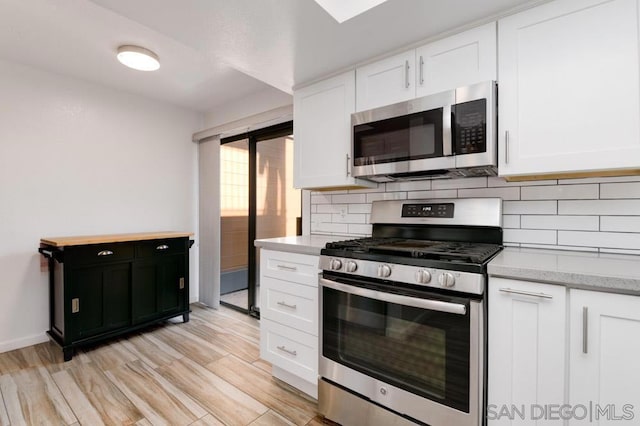 kitchen with light stone countertops, appliances with stainless steel finishes, tasteful backsplash, light hardwood / wood-style flooring, and white cabinetry