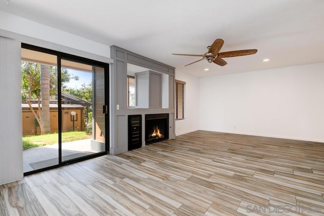 unfurnished living room with a fireplace, light wood-type flooring, and ceiling fan