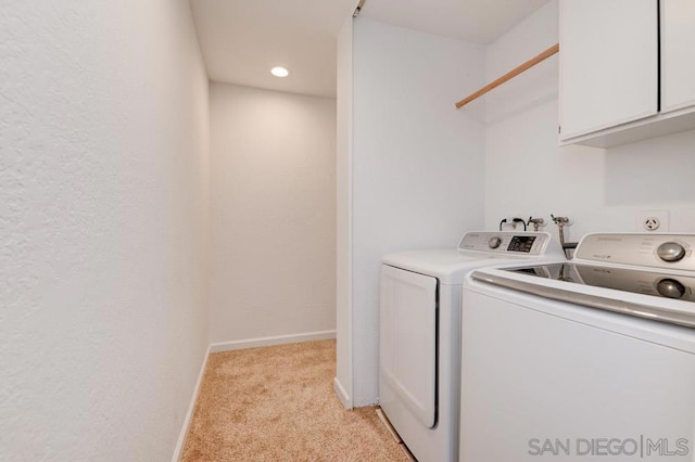 clothes washing area with cabinets, washer and dryer, and light colored carpet