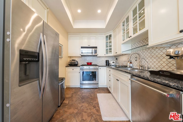 kitchen with appliances with stainless steel finishes, tasteful backsplash, sink, dark stone countertops, and white cabinets