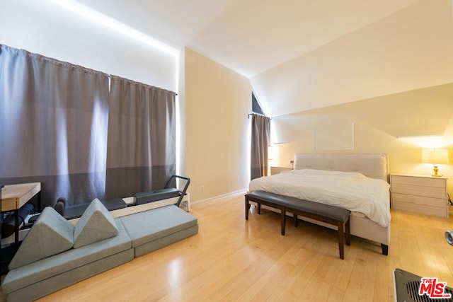 bedroom with vaulted ceiling and light wood-type flooring