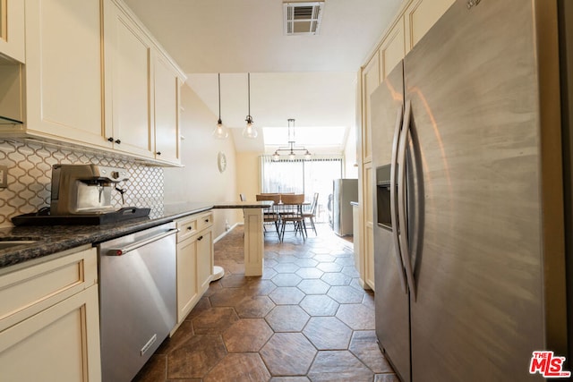 kitchen with pendant lighting, decorative backsplash, appliances with stainless steel finishes, and cream cabinets