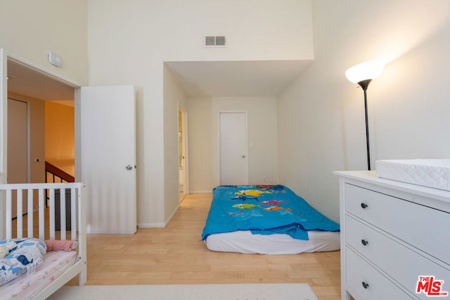 bedroom featuring a high ceiling and light hardwood / wood-style flooring