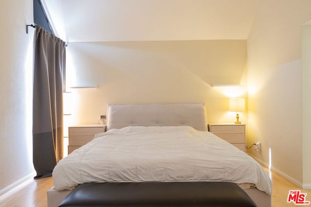 bedroom with light hardwood / wood-style floors and lofted ceiling