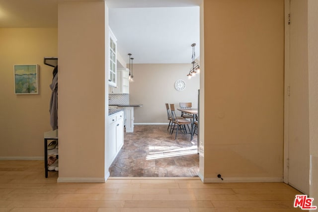 kitchen with white cabinetry, light hardwood / wood-style flooring, a chandelier, decorative light fixtures, and decorative backsplash