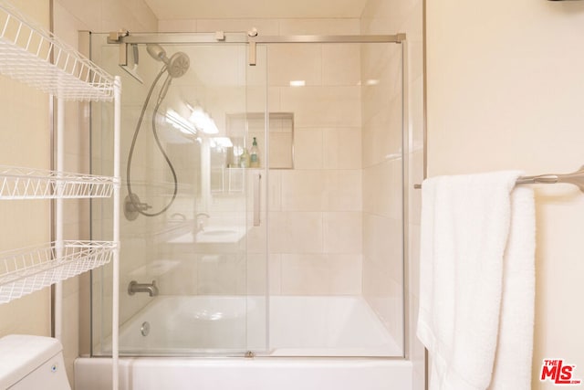 bathroom with combined bath / shower with glass door and toilet