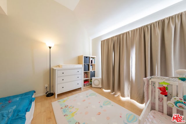 bedroom featuring light wood-type flooring and vaulted ceiling