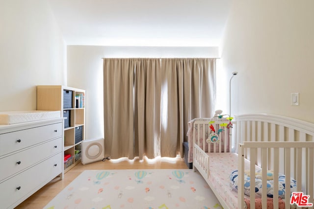 bedroom featuring light hardwood / wood-style floors and a nursery area