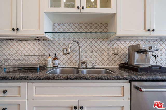 kitchen featuring white cabinets, tasteful backsplash, dark stone countertops, and sink