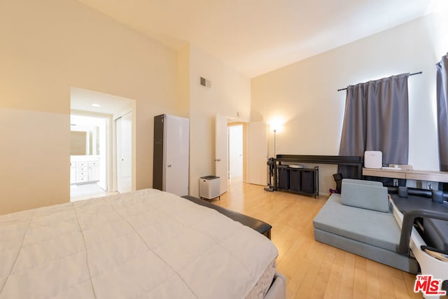 bedroom with light wood-type flooring and high vaulted ceiling