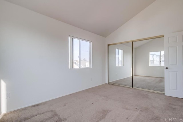 unfurnished bedroom with lofted ceiling, light carpet, and a closet