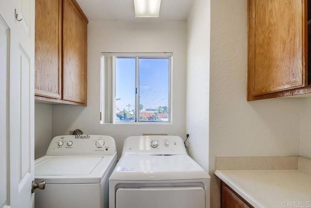 washroom with washing machine and clothes dryer and cabinets