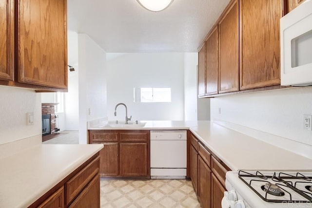 kitchen featuring a fireplace, white appliances, kitchen peninsula, and sink