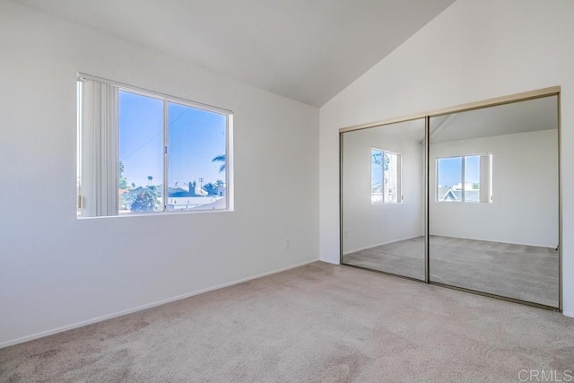 unfurnished bedroom featuring light colored carpet, lofted ceiling, and a closet