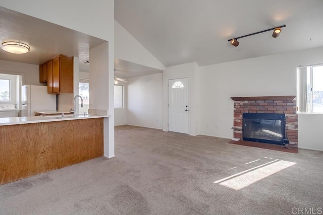 kitchen with white refrigerator, light colored carpet, rail lighting, and a brick fireplace