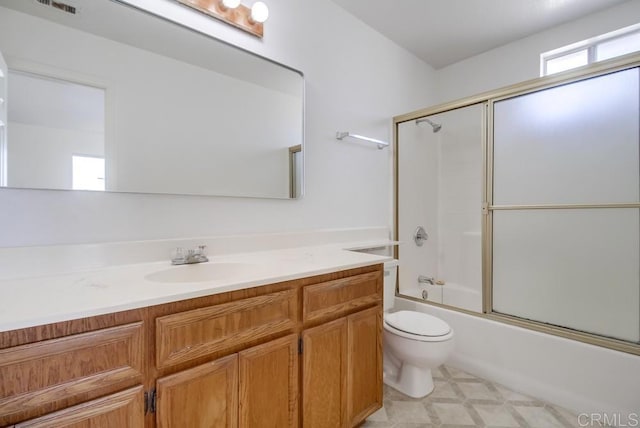 bathroom with toilet, vanity, and shower / bath combination with glass door