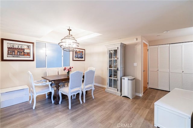 dining space with light hardwood / wood-style floors and a notable chandelier