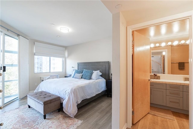 bedroom with access to outside, light wood-type flooring, and connected bathroom