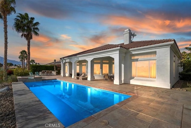 back house at dusk with a patio area