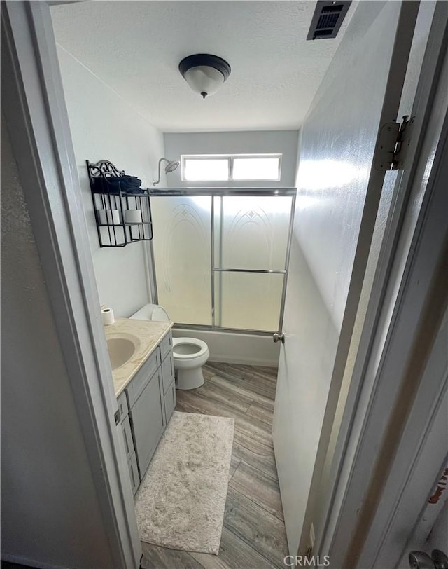 7928 Oakwood Ave, Hesperia, CA 92345 - full bathroom with enclosed tub / shower combo, wood-type flooring, a textured ceiling, toilet, and vanity