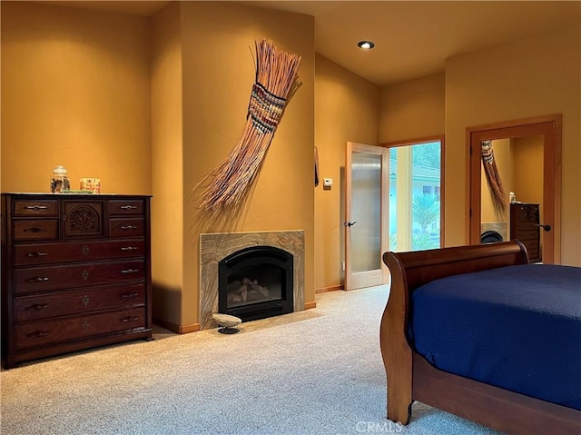 bedroom featuring a high end fireplace and light colored carpet