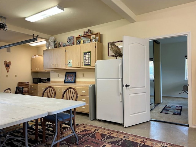 kitchen featuring white refrigerator, light brown cabinetry, and concrete floors