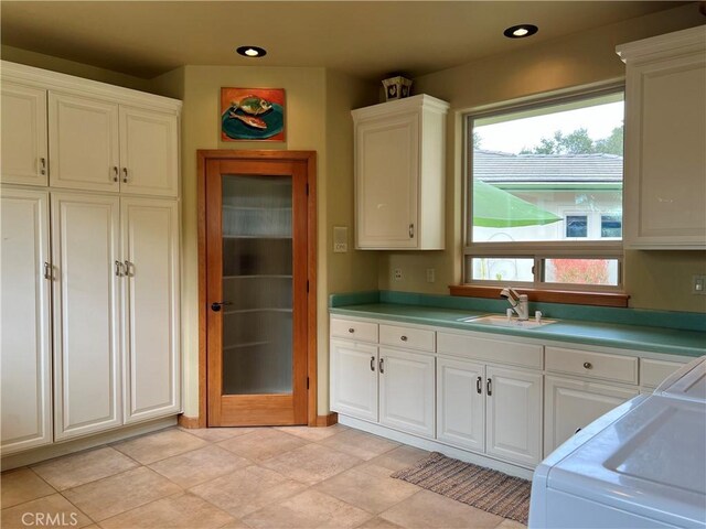 kitchen with white cabinets, light tile patterned floors, white range oven, and sink