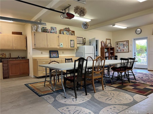 dining space with beamed ceiling and sink