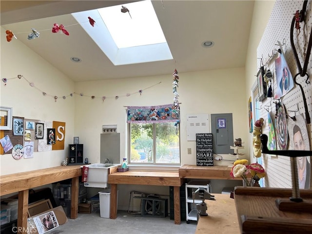 interior space featuring a workshop area, vaulted ceiling with skylight, and concrete flooring