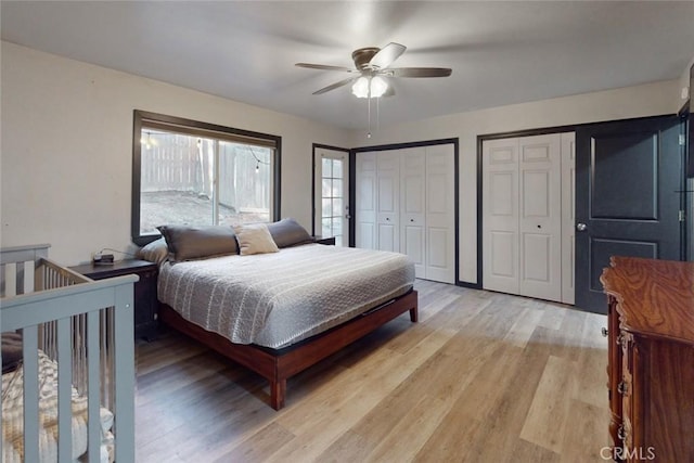 bedroom featuring ceiling fan, two closets, and light hardwood / wood-style flooring