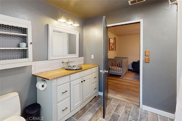 bathroom with hardwood / wood-style floors, vanity, and toilet