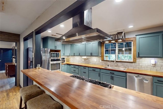 kitchen with sink, light hardwood / wood-style flooring, butcher block counters, island exhaust hood, and stainless steel appliances