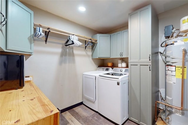 laundry area with light hardwood / wood-style floors, water heater, cabinets, and independent washer and dryer