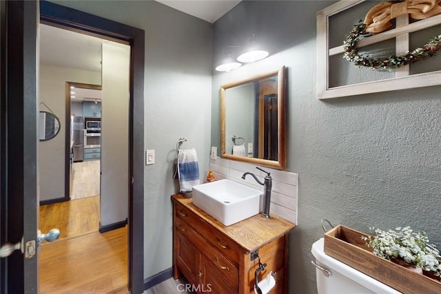 bathroom featuring wood-type flooring, vanity, and toilet