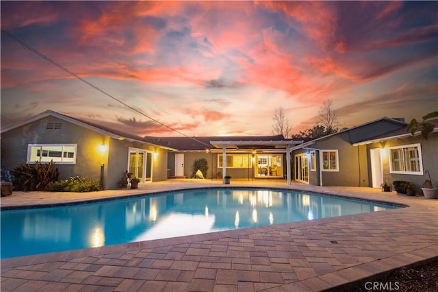 pool at dusk with a patio area