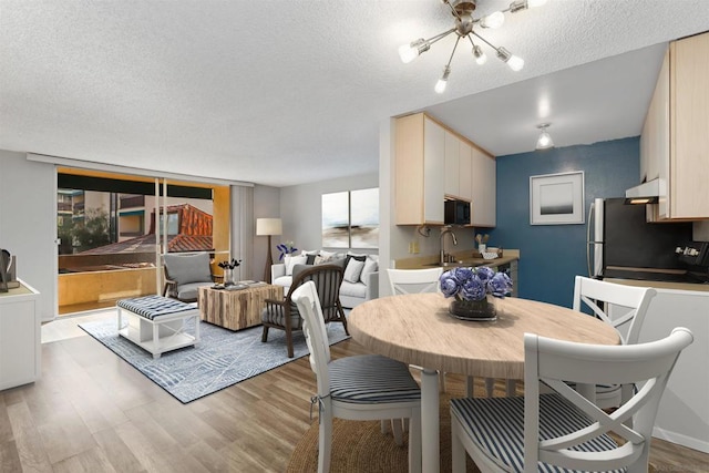 dining space with a chandelier, a textured ceiling, light hardwood / wood-style floors, and sink