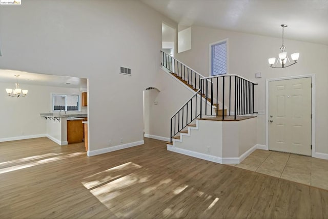 entryway featuring a chandelier, light wood-type flooring, high vaulted ceiling, and sink