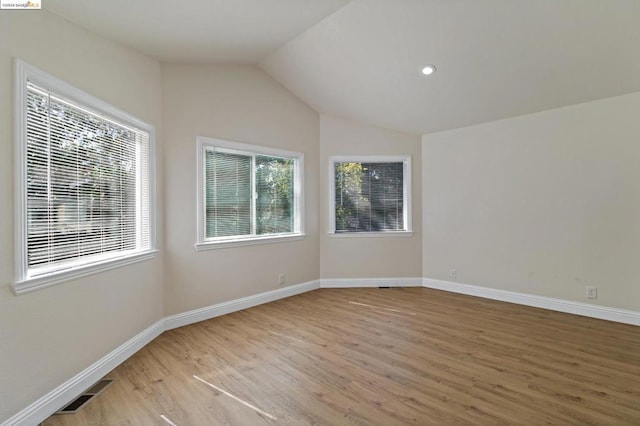 spare room with lofted ceiling and light wood-type flooring