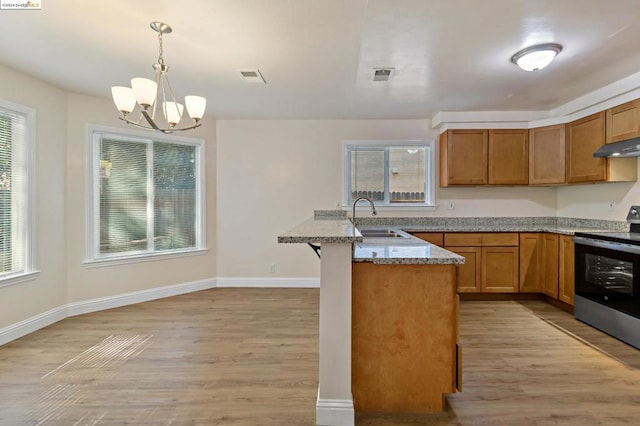 kitchen featuring stainless steel range, light hardwood / wood-style flooring, a notable chandelier, and sink