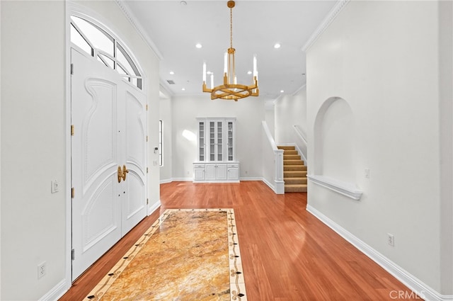 entryway with a notable chandelier, light hardwood / wood-style floors, and ornamental molding