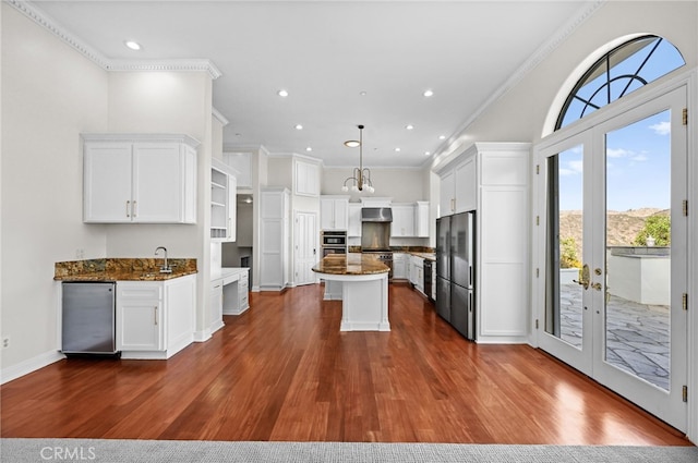 kitchen featuring dark stone counters, crown molding, white cabinets, a center island, and stainless steel refrigerator