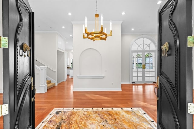 entryway with light hardwood / wood-style flooring, an inviting chandelier, and ornamental molding